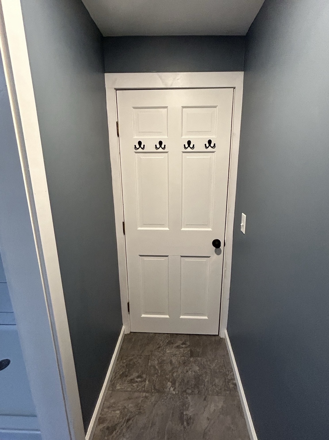 Finished hallway with white door and wall hooks, by Three Lakes Builders LLC