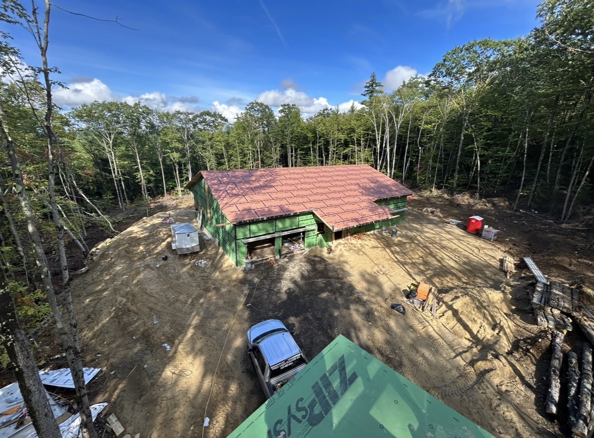 Overhead view of a new home under construction on a wooded lot, by Three Lakes Builders LLC
