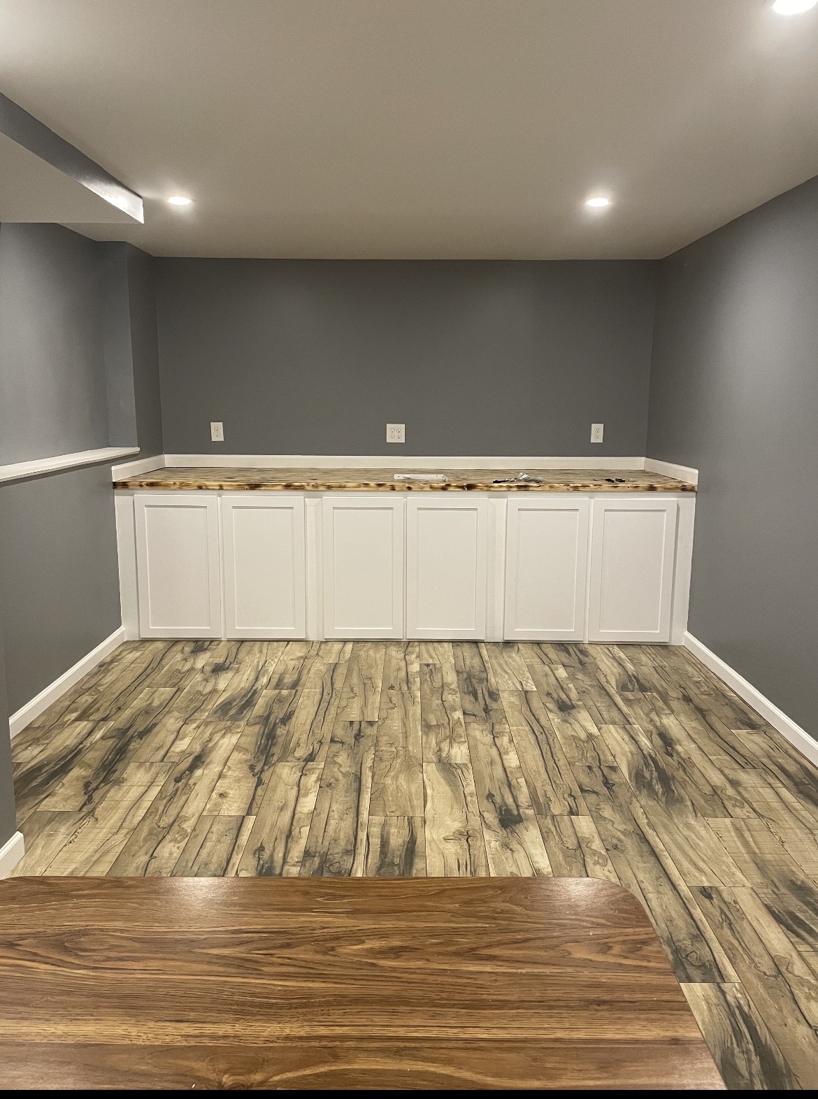 Finished basement room with wood-look flooring and built-in cabinets, by Three Lakes Builders LLC