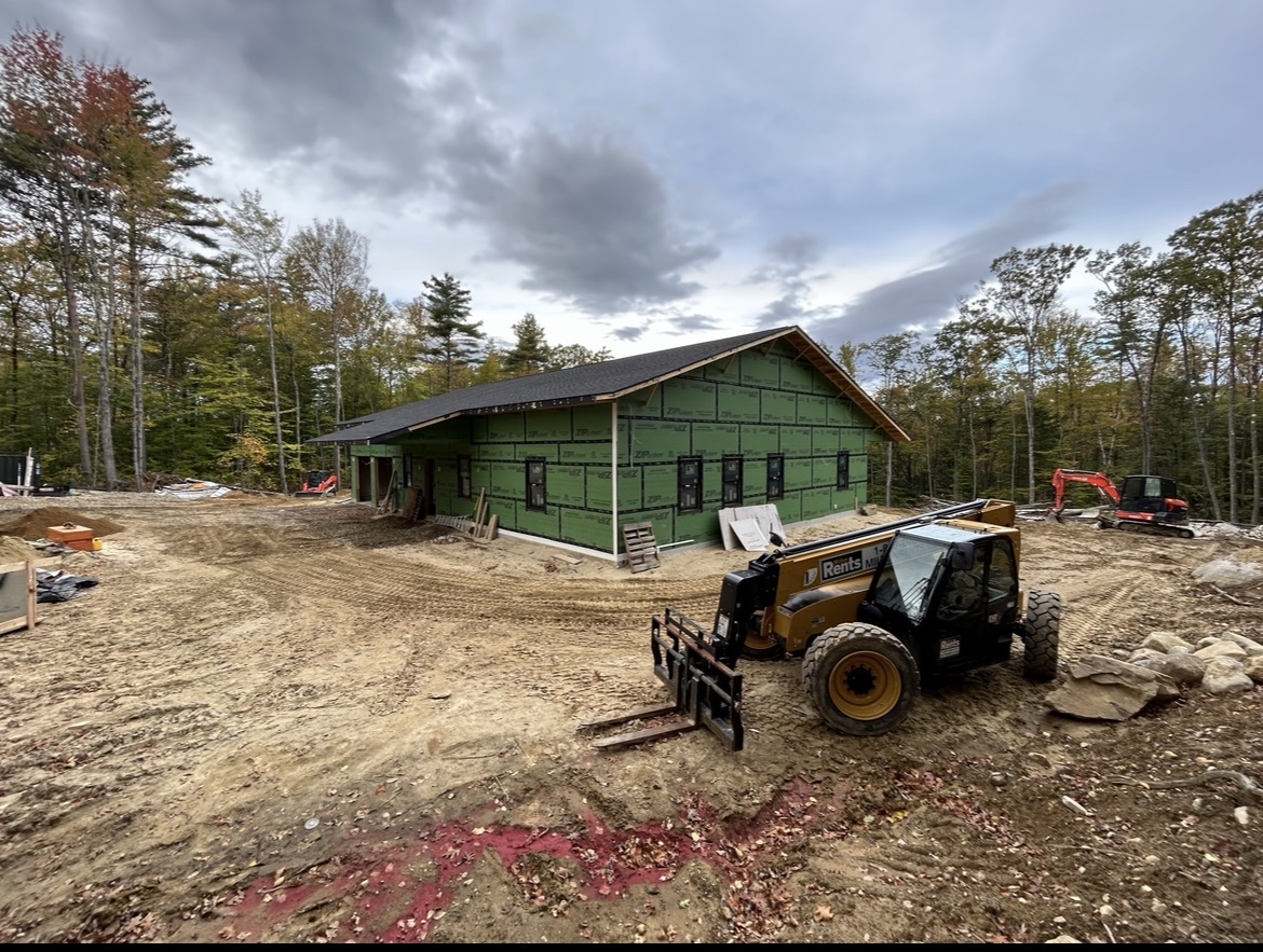 New home framed with green sheathing and equipment on site, by Three Lakes Builders LLC
