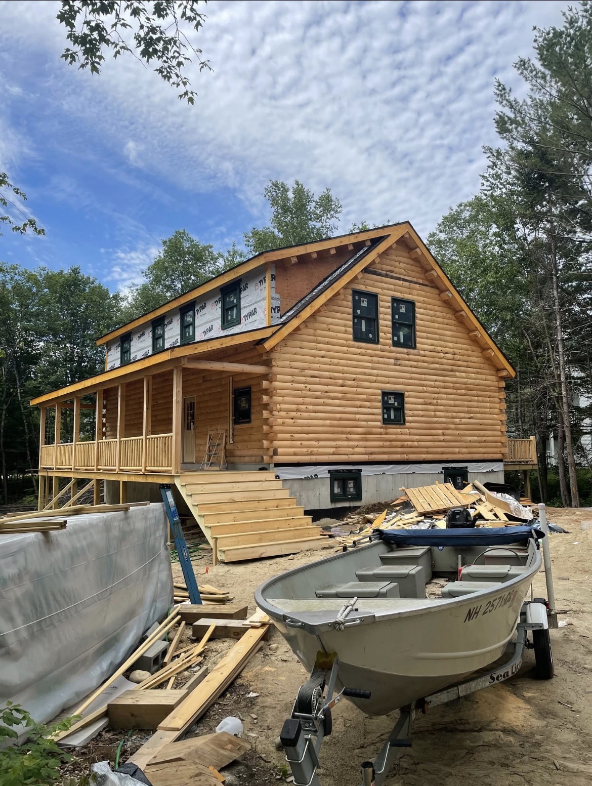 Log home under construction with a covered porch and wooden front steps